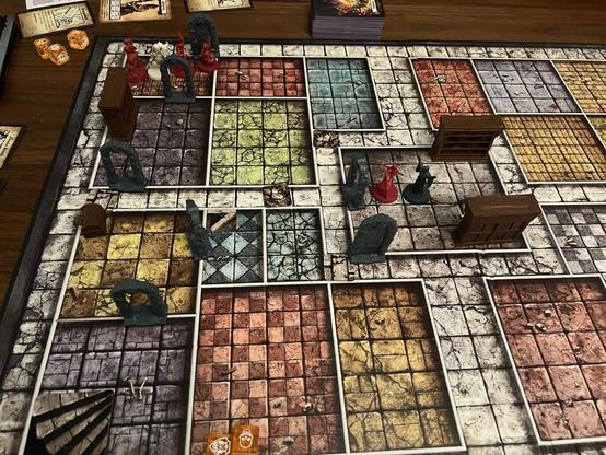 A picture of a HeroQuest game in progress. 

A monk is in the center room fighting a cultist between two bookcases. 

A barbarian, a warlock, and a rogue fighting a skeleton in the room in the upper right corner. 

A falling block trap in the hallway separates the two groups.