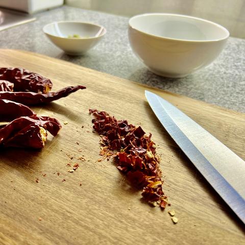 Getrocknete Rote Chili werden auf einem Holzbrett zerkleinert