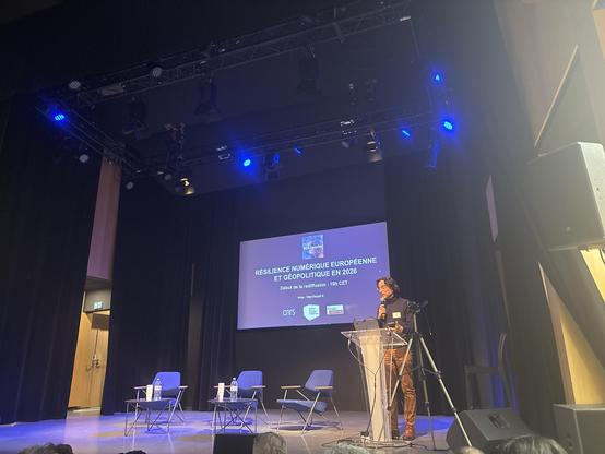 Photo de la scène, un écran affiche le titre de la soirée : résilience numérique européenne et géopolitique en 2026. David Chavalarias est au pupitre.