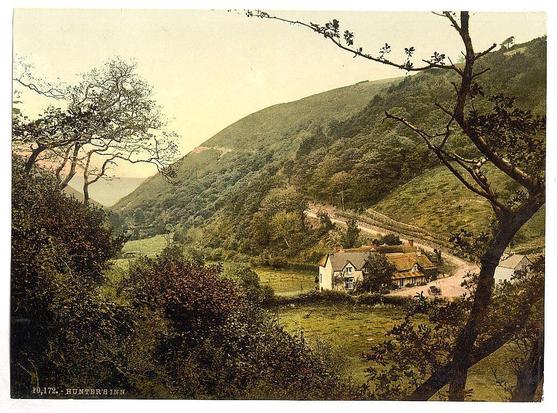 This image is a vintage photograph depicting a rural landscape. The scene features rolling hills covered with dense vegetation, including trees and bushes in varying shades of green, indicating lush foliage typical of temperate climates. In the foreground, there's an expansive view of grassy fields that transition into patches of trees.

Prominently located within this natural setting is Hunter’s Inn, a quaint village inn set amidst sprawling grounds. The building appears to be constructed with traditional English architecture in mind—two-story wooden structures with pitched roofs and visible chimney stacks. Windows reflect the surrounding light, suggesting they are made from translucent glass.

A winding path or road leads up the hillside towards another smaller structure, possibly part of the inn complex. This suggests accessibility for visitors arriving by foot or horse-drawn carriage—a common mode of transport in rural areas during that era.

The overall atmosphere is serene and picturesque, with a sense of peaceful isolation from urban life—idealized as an idyllic retreat into nature. The image’s vintage quality, including sepia tones and the style of photography typical of the late 19th century to early 20th century, adds historical context.

There's no human presence or movement captured in this still shot; it emphasizes tranquility and untouched beauty rather than [...]