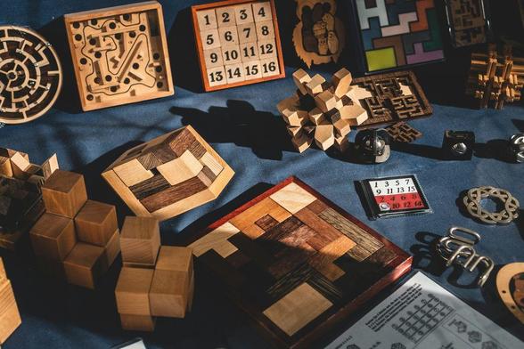 A collection of fine wooden and metal puzzles and mazes displayed on a blue cloth.