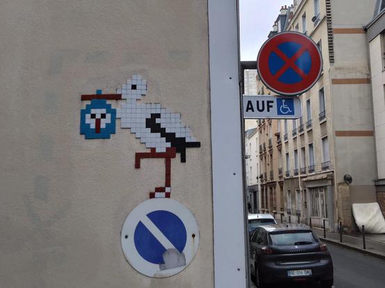 Tile art of a stork holding a baby stork in her beak, standing on a forbidden parking sign.