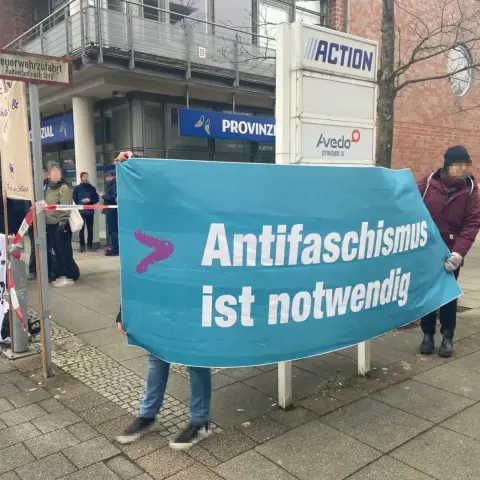 Ein Tranpi ist zu sehen auf dem "Antifaschismus ist notwendig" drauf steht.