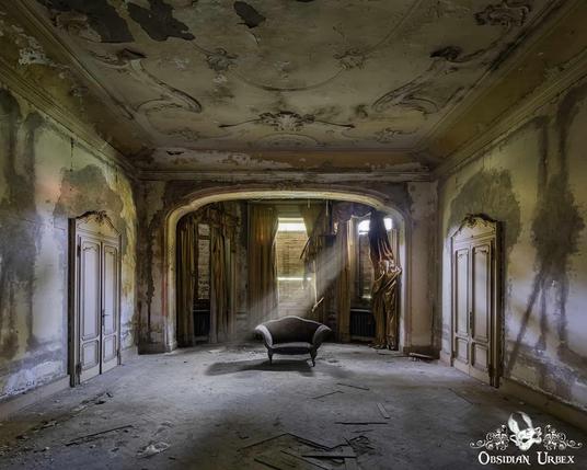 A photo shows a decrepit room with an ornate ceiling and tattered curtains. Sunbeams illuminate a lone chair.