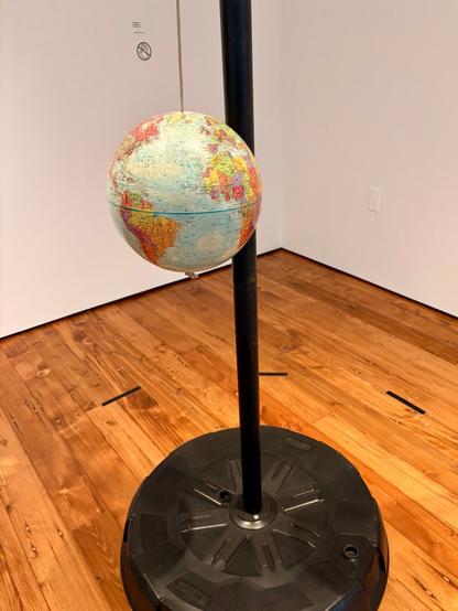 A globe is attached to a tetherball pole.