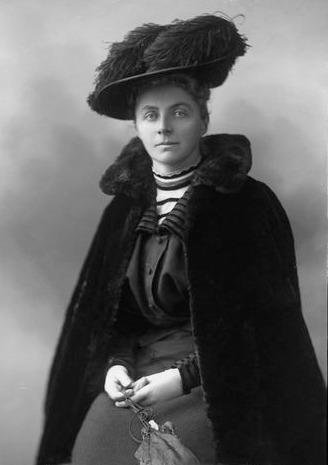 Studio portrait of Emily Hobhouse. She is a white woman in a cloak and a big hat.