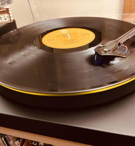 A vinyl record spins on a turntable, with a bright yellow label at the center.