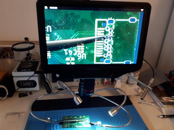 A picture of a desk with a circuit board under a microscope.
The microscope screen shows the USB-c connector footprint.
The circuit board is an unassembled SucréLA prototype.