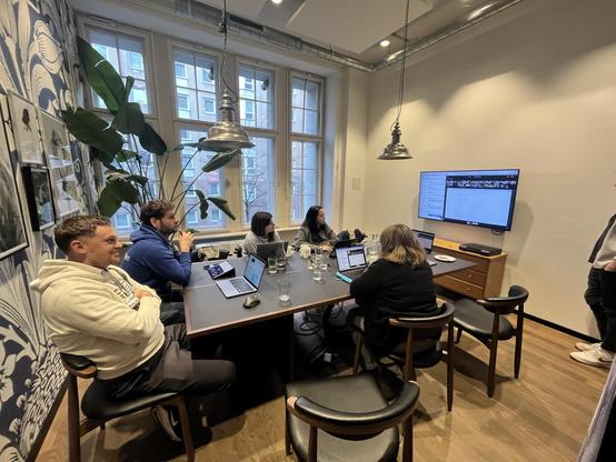OpenProject team members gathered around a table with laptops during an in-person planning meeting, combining remote work practices with face-to-face collaboration.