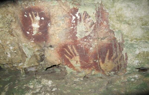 photo of pointy-fingered hand stencils on a cave wall