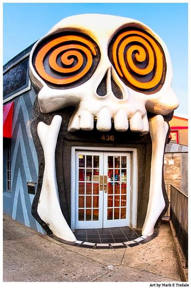Digital photograph that shows the entrance to the Vortex restaurant in Atlanta's Little Five Point's neighborhood. The large double door is framed by a giant skull with googly eyes. The door appears to be within the open mouth of the skull.