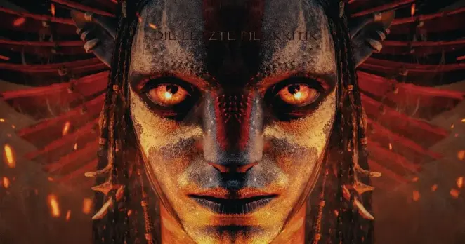 Na'vi vom Feuervolk aus dem Film "Avatar: Fire & Ash". Auf der Stirn des Aliens mit prächtigem zeremoniellem Kopfschmuck steht "Die Letzte Filmkritik" geschrieben. Drumherum Feuer und Funken.