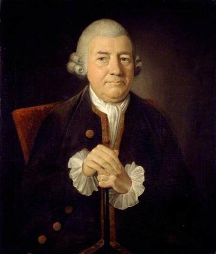 Portrait of an 18th-century man wearing a dark coat with white ruffled cuffs, seated with hands clasped.