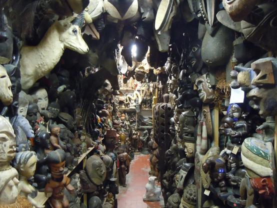 Eion enger Gang in einem Laden lässt wenig Platz zum Laufen. Links und Rechts wie auch am Ende des Gangs, hängen hunderte Objekte, Skulpturen, Masken, Ausgestopfte Tiere etc. Chaos pur , oder doch Kitsch?