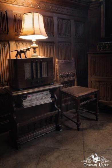 A dimly lit room featuring a vintage radio, lamp, and chair, evoking a sense of nostalgia