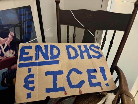 My protest sign, hanging over my rocking chair at work.