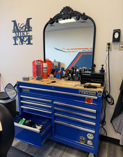 A blue toolbox being used as a barber stand with a mirror.