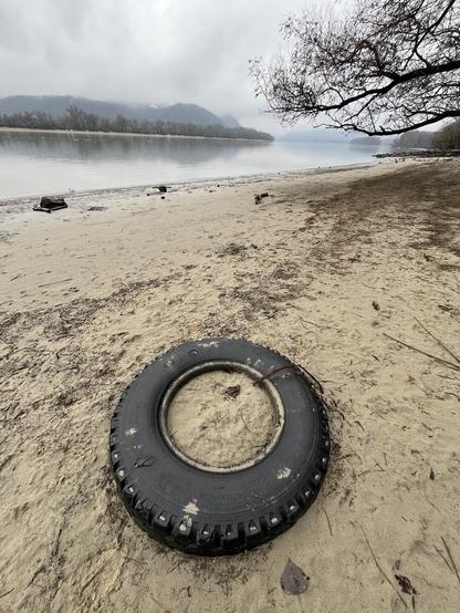 Car tire partly embedded a sandy riverbank.