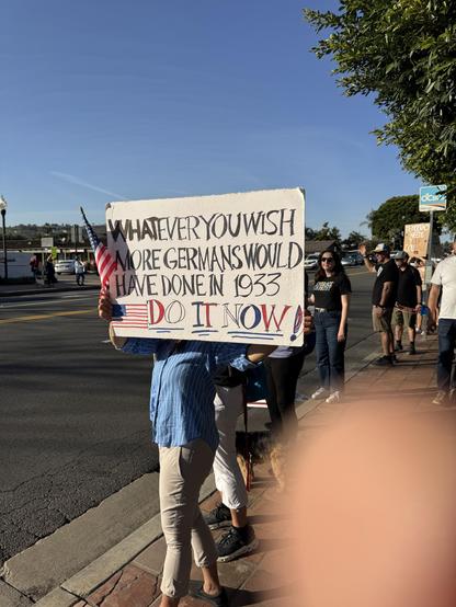 Protestor holding a sign reading “Whatever you wish more Germans would have done in 1933, do it now!!” San Juan Capistrano, CA 2026-01-30