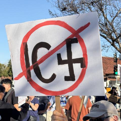 Protestor holding up sign featuring a red slash through a red circle containing the word “ICE” with the “E” replaced by a swastika, San Juan Capistrano, CA 2026-01-30
