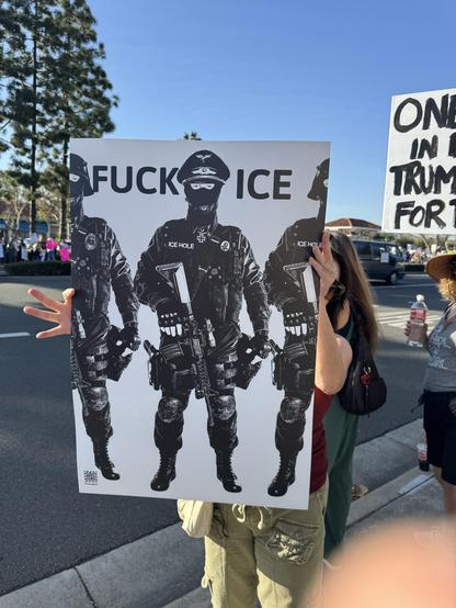 Protestor holding sign featuring stark, monochrome images of armed,  SS-like figures under the words “Fuck ICE”, San Juan Capistrano, CA 2026-01-30