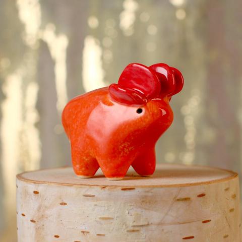 A small red ceramic creature with an orange body and a head of red plates.