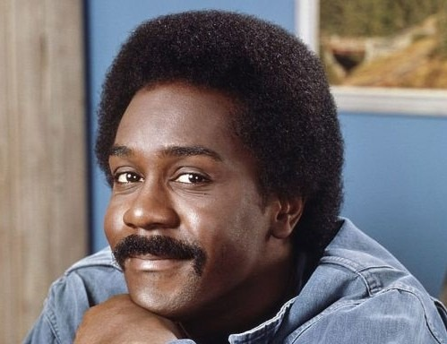 photo of Demond Wilsn in a blue shirt, with a half smile, from the 1970's