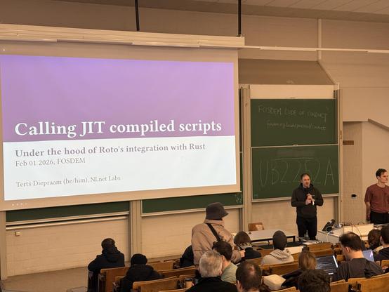 Photo of the stage showing a screen with the title Calling JIT compiled scripts