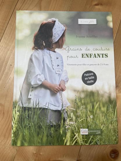 Cover des Buches „Grains de couture pour Enfants“ von Ivanne Soufflet: 

Mädchen mit weiser Bluse in grüner Wiese.