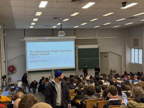 Photo of a room of people with a screen saying: Ty: Adventures of type-checking Python using Rust