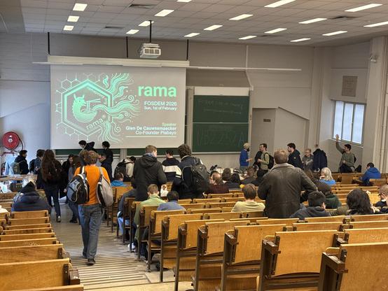 Photo of a deveoom woth lots of empty seats. The screen shows a slide with the title Rama