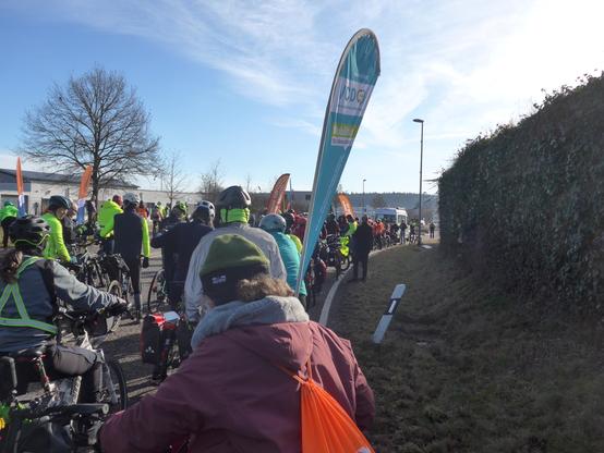 Viele Menschen mit Fahrrädern stehen auf einer Straße.