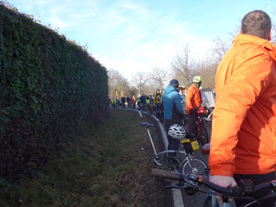 Viele Menschen mit Fahrrädern stehen auf einer Straße.