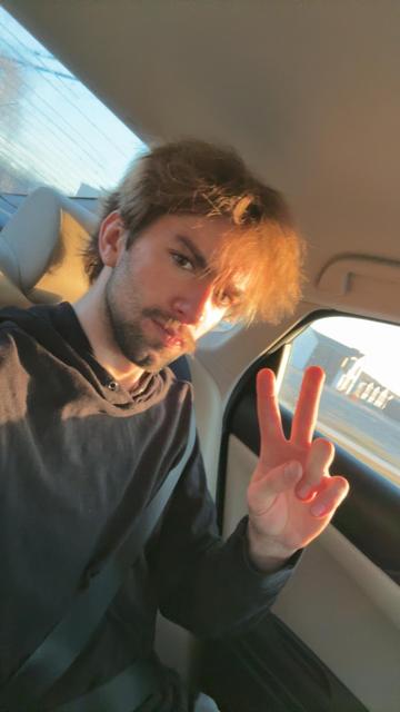 A photo of me in the back seat of a car with ✌️ held up