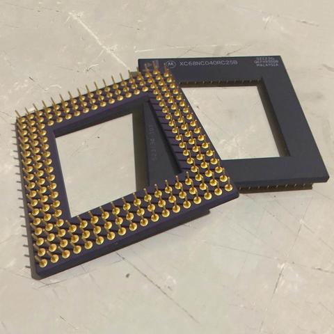 A photo of two CPUs on a desk, one pin side down with another pin side up leaning over it. Both CPUs have a large square missing out of the centre, and the label on top of the bottom CPU reads XC68NC040RC25B