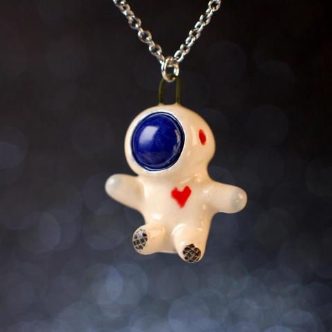A little ceramic floating astronaut with a blue faceplate and a heart on its chest.