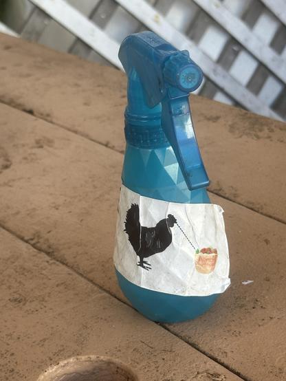 Blue water spray bottle with a stylized chicken looking at a poke bowl