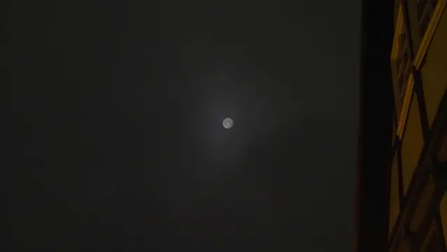 Mond als milchige Scheibe am dunkelgrauen Himmel