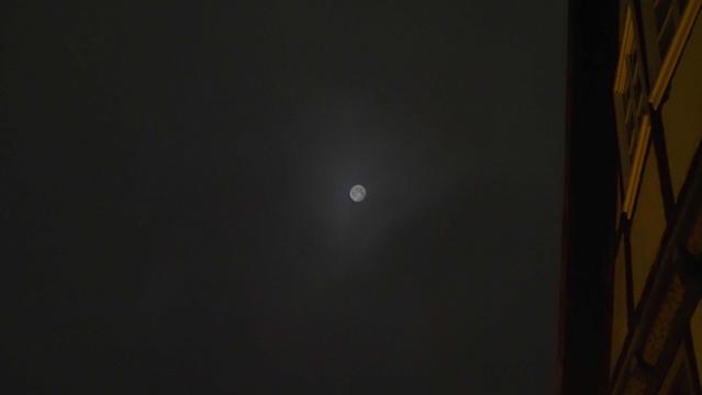 Mond als milchige Scheibe am dunkelgrauen Himmel