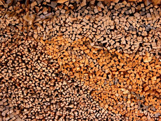Eine ganz große Wand von sorgsam aufgeschichteten Holzscheiten, dicht an dicht. In der Mitte ein farblicher Einschub von rechts einer anderen Sorte Holz, rötlicher, evtl Lärche. Im Allgäu 2005.