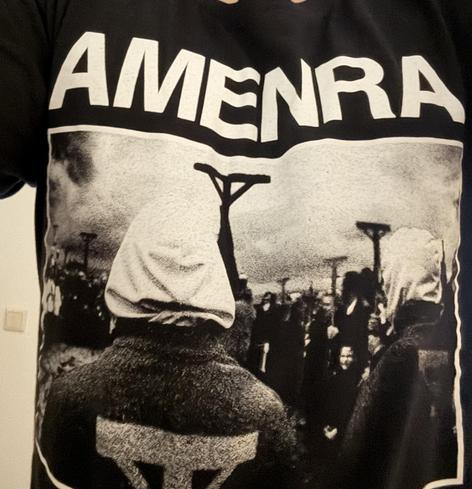 Black Tshirt with b/w print of a crowd people, backs turned towards the camera, carrying Thou crosses. Amenra in all caps is printed above the photo.