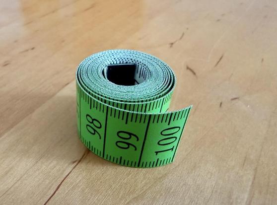 Ein aufgerolltes Maßband bei 100cm abgeschnitten