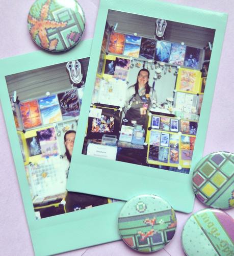 a photo of two instant photos showing Dinchen at her booth, surrounded by a bunch of buttons