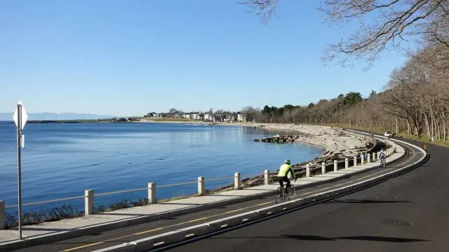 A new two-way quick-build protected bike lane on Dallas Road in Victoria, BC. Ross Bay Pebbles Beach is on the left and the Ross Bay Cemetery is on the right.