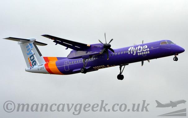 Low side view of a high-winged, twin propellor-engined airliner flying from left to right at a low altitude, with undercarriage lowered and flaps extended from the rear of the wings, suggesting it is about to land.
The plane is almost entirely purple, with an orange and purple band around the rear fuselage, and a white tail-cone and tail.
There are white., billboard-style "FlyBe" titles above 6 white dots on the side of the forward fuselage, with similar diagonal titles in light and dark blue on the tail, over 2 orange, 2 red, and 2 purple dots.
The white titles are also inverted on the underside of the fuselage.
The engine pods mounted out on the wings are also purple, with the main undercarriage hanging down on long, spindly legs from the rear.
The black registration "G-JECZ" is on the side of the tail-cone right at the rear.
Flat grey clouds fill the rest of the frame.