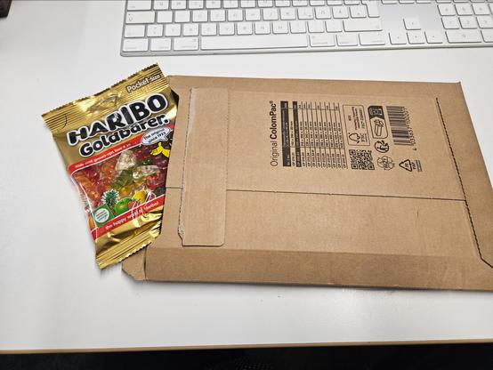 A photo of a small shipping envelope with a bag of Haribo Goldbären peeking out of it.