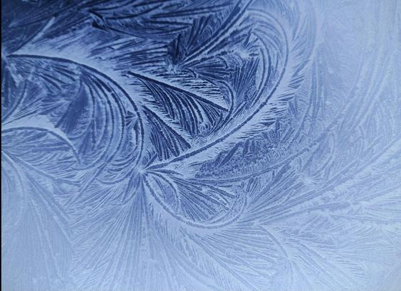 Photo of intricate, swirly feathers painted on my frost on a reflective surface.