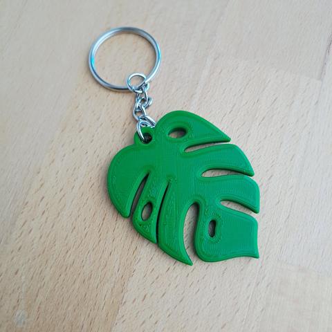 Un porte-clés en forme de feuille de Monstera vert foncé.