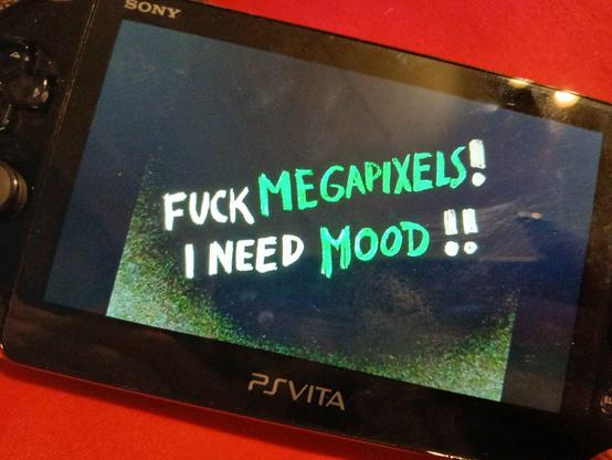 PSVita displaying a handwritten white and green text on a noisy black background. "FUCK MEGAPIXELS! I NEED MOOD!!"