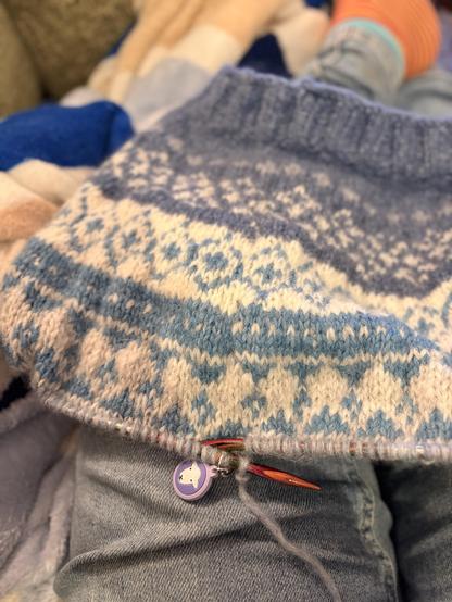 Blue & white fair isle knitting sitting on my lap under rather yellowy artificial light.